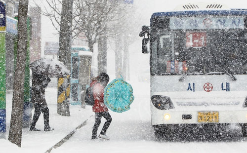 ▲ 6일 대설주의보가 내려진 영동 중북부지역에 갑자기 많은 눈이 쏟아지자 우산을 쓴 시민들이 종종걸음으로 시내버스에 오르고 있다.