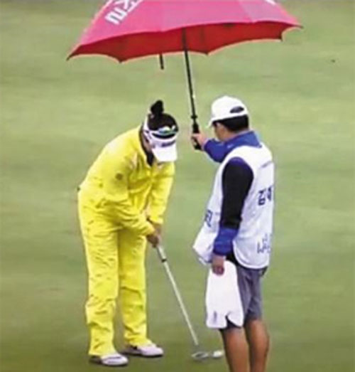 김예진이 7번홀에서 퍼팅 스트로크를 하는 동안 캐디인 아버지가 우산을 씌워주고 있다. 사진=SBS골프 캡처