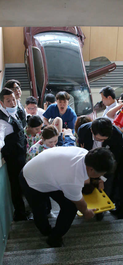 22일 오후 경기도 고양시 일산백병원 주차장을 나오던 차량이 병원 건물로 돌진, 계단 아래로 추락한 직후 병원 관계자들이 환자를 이송하는 모습