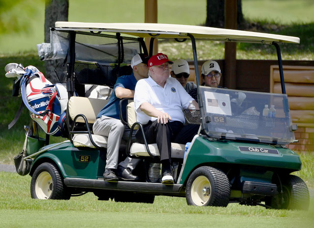 트럼프 대통령이 아베 총리가 운전하는 카트를 타고 있다.