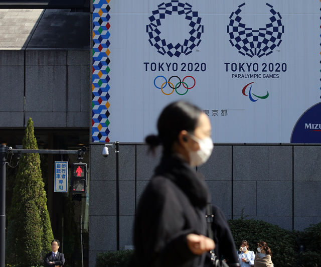 마스크를 쓴 여성이 9일 올림픽 홍보물이 설치된 도쿄 시내를 걷고 있다. [출처 : 연합]