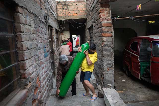 지난 11일 페루 리마에서 7시간 동안 기다린 뒤 산소통을 충전해온 한 남성이 산소통을 집으로 힘겹게 옮기고 있다. [AP=연합]