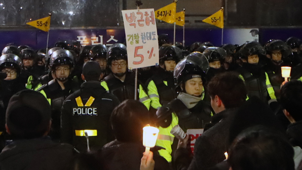 3일 오후 서울 종로구 광화문광장에서 열린 촛불집회에 참가한 한 시민이 손팻말을 들고 경찰 앞에 서 있다.