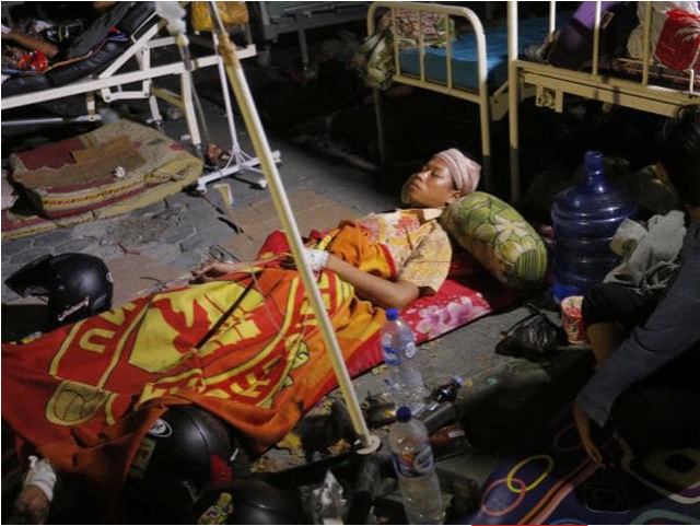 지진에서 살아남은 환자들은 치료 시설 부족으로 병원 마당이나 폐허 속에서 치료를 받고 있다.사진은 병원 밖 길바닥에서 치료받고 있는 인도네시아 여성의 모습.(출처:AP=연합뉴스)