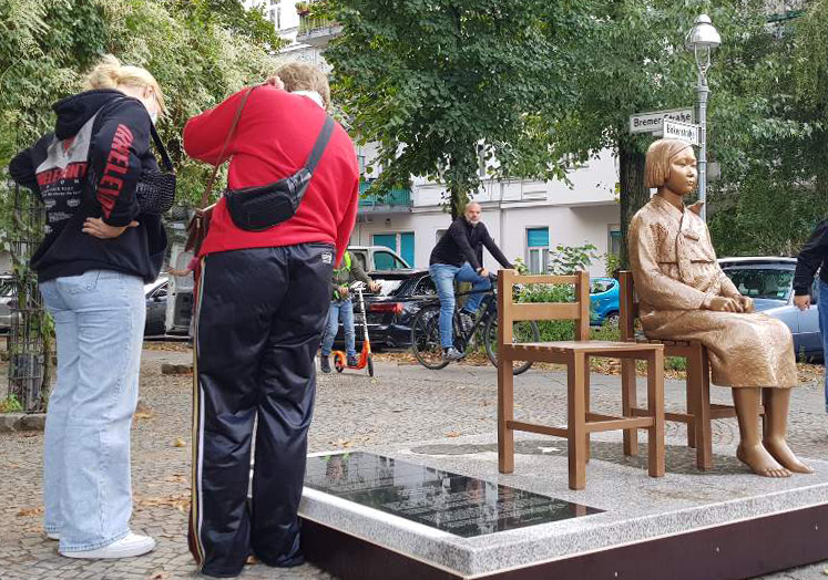 지난 25일 독일 수도 베를린에 설치된 ‘평화의 소녀상’에 쓰인 비문을 지나가던 시민들이 읽고 있다.