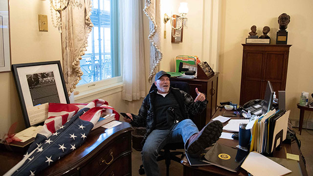 트럼프 대통령 지지자가 낸시 펠로시 민주당 하원의장 집무실에 난입해 테이블 위에 다리를 올리고 포즈를 취하고 있다.[사진=AFP 연합뉴스]