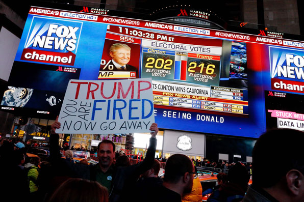 힐러리 클린턴 후보 지지자들이 개표방송 진행되는 CNN 앞에서 도널드 트럼프를 비난하는 팻말을 들고 환호하고 있다. (사진=AP)