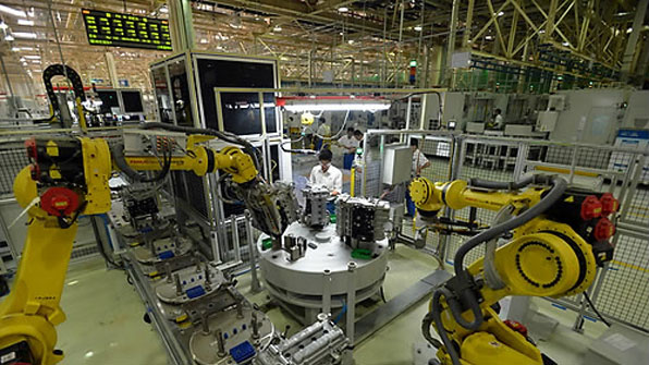 중국 후안성에 있는 GM 중국공장에서 근로자가 로봇팔을 이용해 엔진을 조립하고 있다.