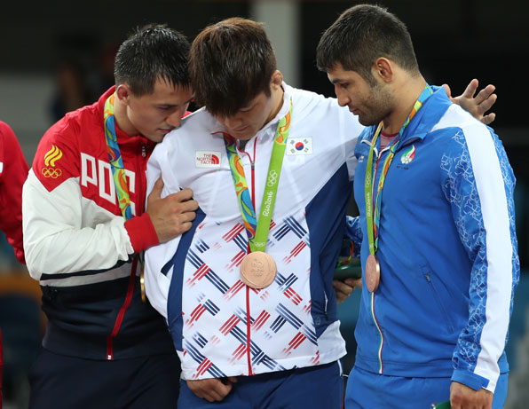 김현우가 부상한 오른쪽 팔을 점퍼 속에 넣고 시상식 단상에서 금메달을 차지한 라이벌 로만 블라소프(러시아)의 격려를 받고 있다. (2016.8.15)