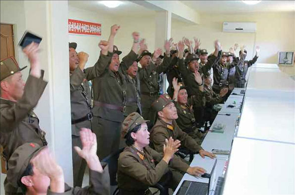 북한의 로켓엔진 실험 이후 관계자들이 손뼉을 치며 환호하고 있다. (출처: 노동신문)