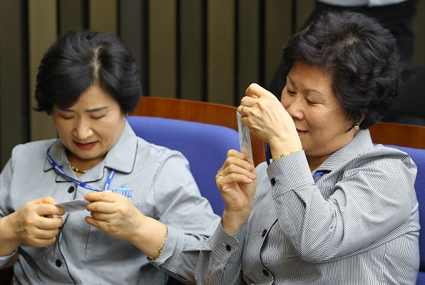 국회 직원 신분증을 받은 뒤 내용을 살펴보고 있는 환경미화 근로자 김영숙 씨 (오른쪽)