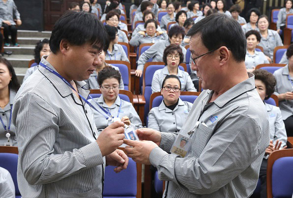 국회 직원 신분증을 받은 뒤 내용을 살펴보는 근로자들