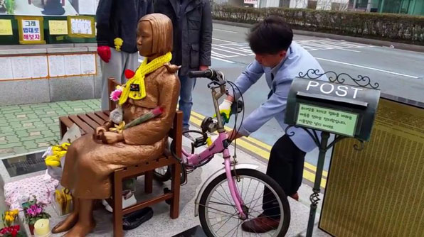 5일 오전 부산 동구 일본영사관 앞에서 부산겨레하나 회원이 ‘평화의 소녀상’에 자전거를 묶어 놓은 자물쇠를 절단기로 자르고 있다. 소녀상 설치에 반대하는 사람들이 5일 새벽에 중고 자전거를 묶고 달아났다.