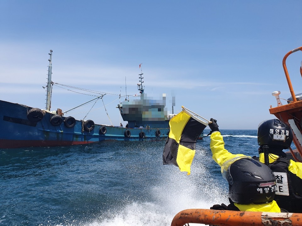 해경 대원이 조업일지를 조작한 중국 어선을 세우고 있다.(군산해경 제공)