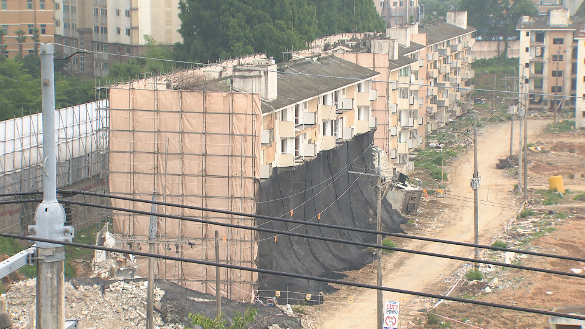 광주광역시 북구 운암3단지 철거현장.  해체계획서와 달리 아래층부터 철거한 아파트를 가림막으로 가려놓은 모습.