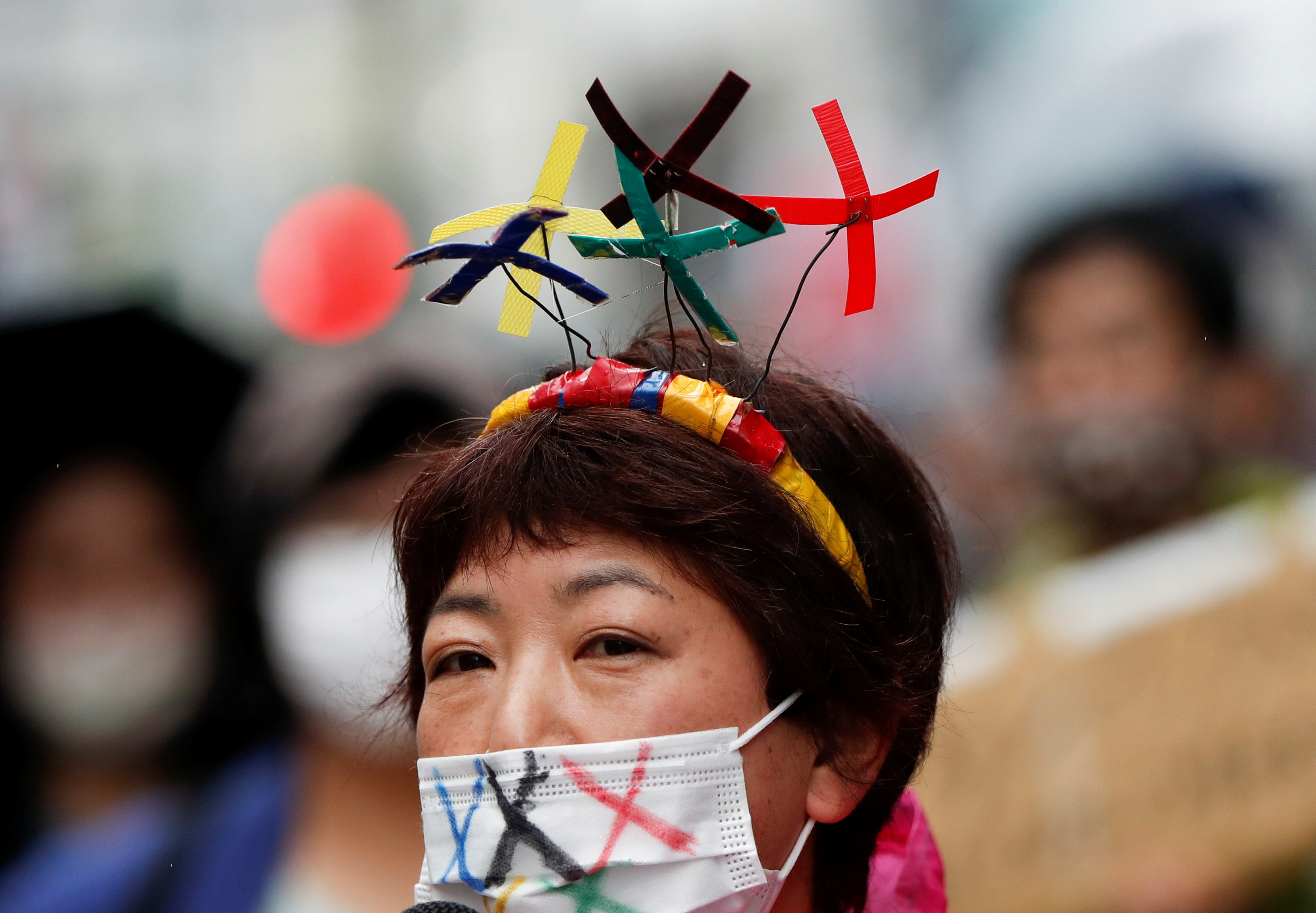 도쿄올림픽 개막식이 한 달여 앞으로 다가온 지난 19일 일본 도쿄에서 올림픽 반대 시위에 참가한 한 시민이 'X' 표시의 머리띠와 마스크를 한 채 구호를 외치고 있다. 〈도쿄=로이터〉