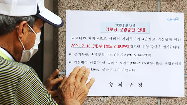 13일 서울 송파구 한 경로당에서 어르신이 주민센터 직원과 함께 사회적 거리 두기 격상에 따른 경로당 폐쇄 안내문을 부착하고 있다.