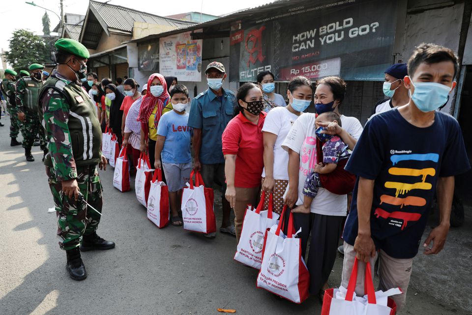 인도네시아 자카르타의 주민들이 생필품 지원을 받기위해 줄을 서 있다. 군인들이 통제한다.사진 AFP