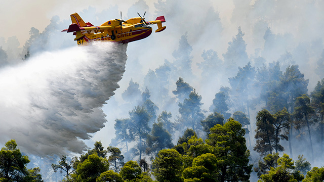 8일 그리스 에비아 섬 엘리니카 마을 근처에서 산불이 나면서 소방헬기가 숲에 물을 뿌리고 있다.