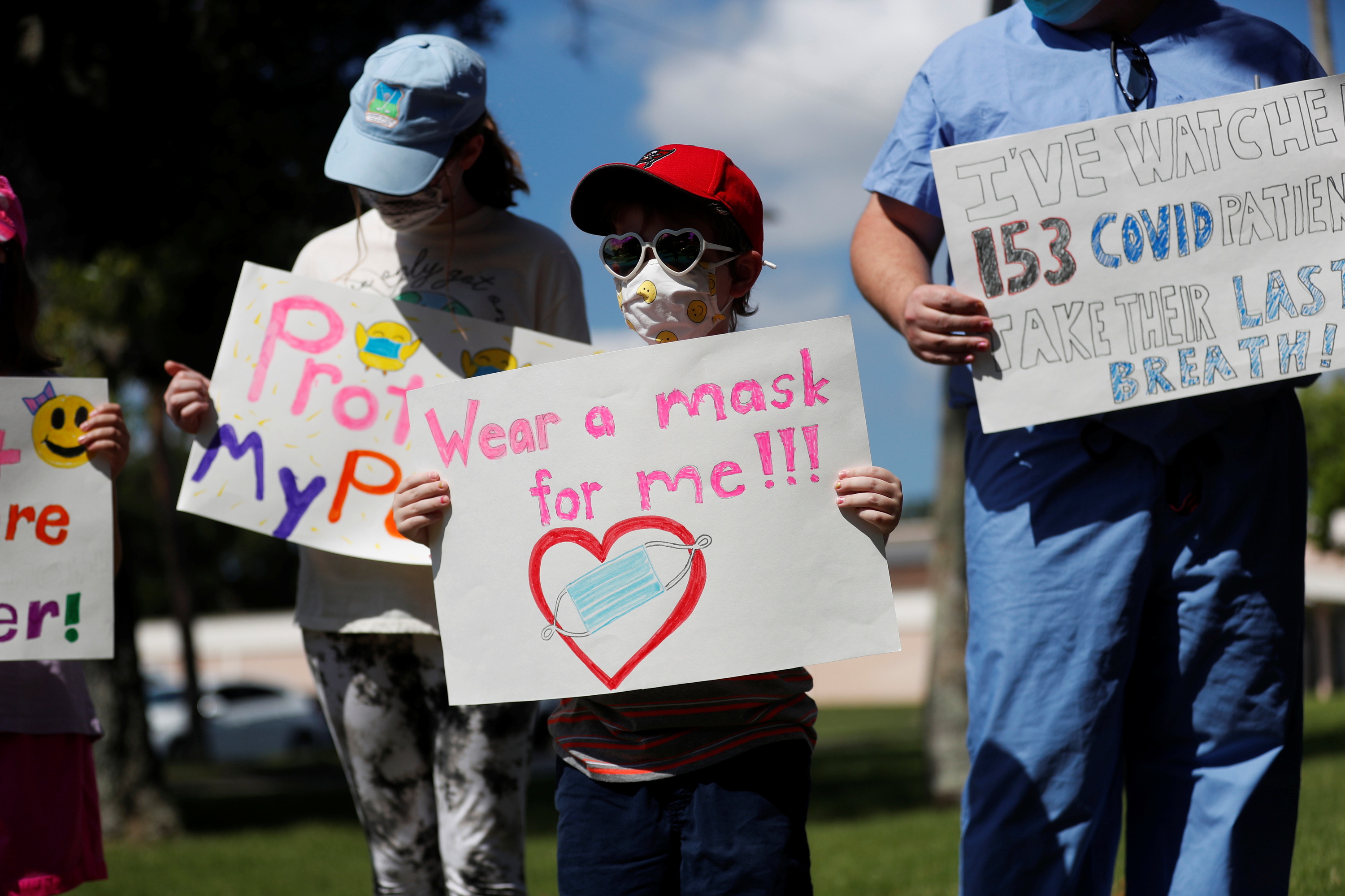 9일 플로리다주의 한 학교에서 열린 이사회 워크숍에 앞서 마스크를 쓴 사람들이 ‘마스크 착용 의무화’ 시위를 하고 있다.