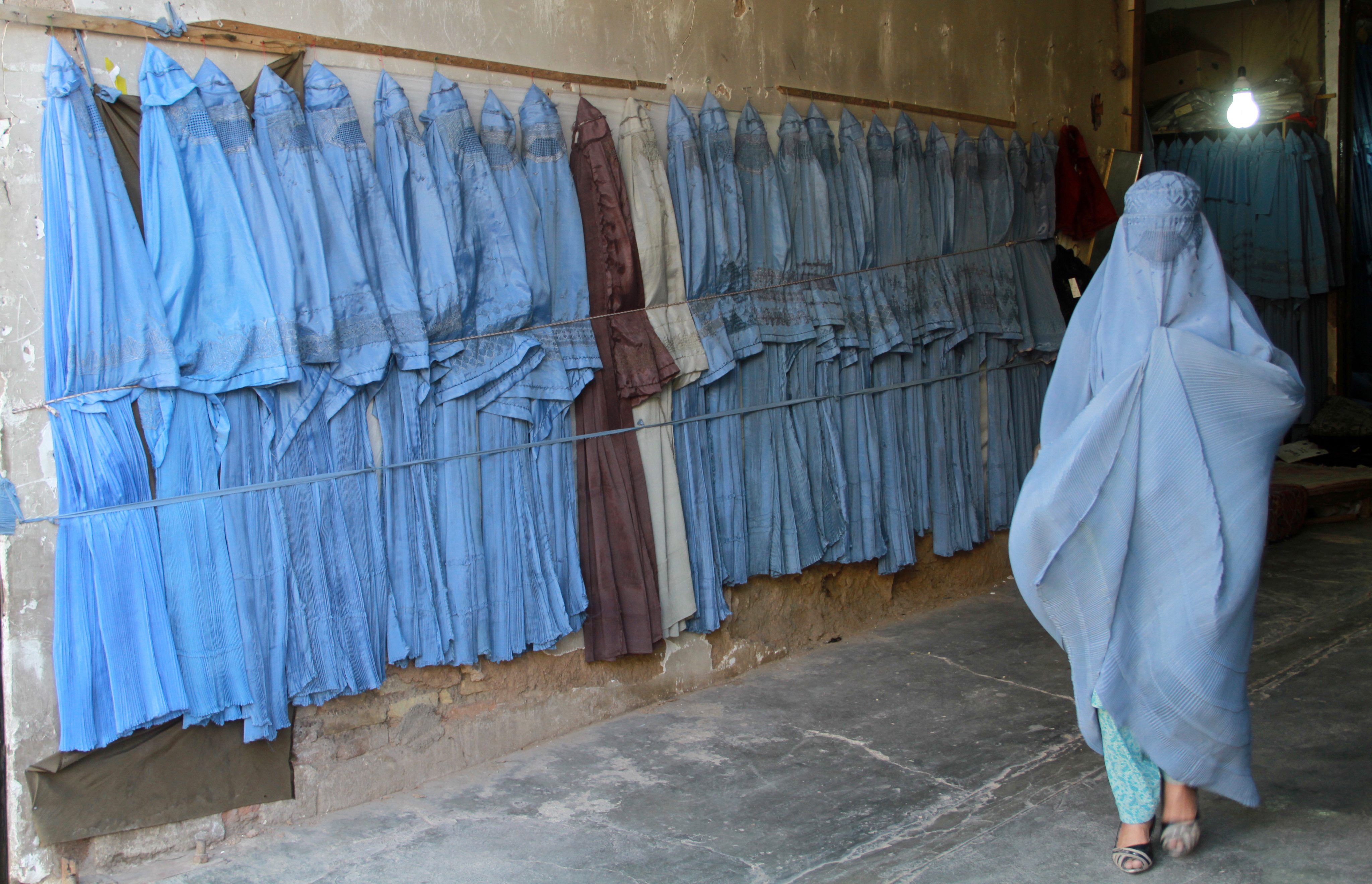부르카를 판매하는 옷가게를 지나는 아프가니스탄 여성
