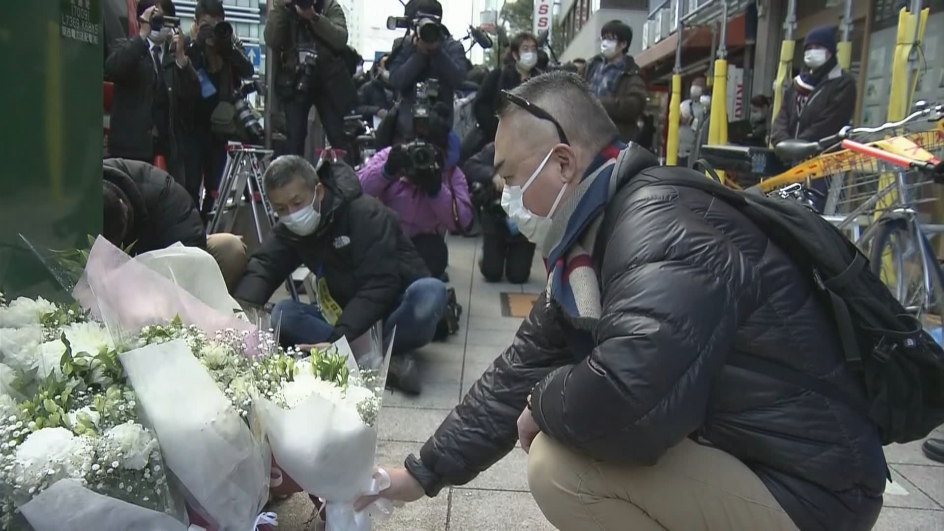 12월 18일 화재 참사 현장 앞에 희생자의 영혼을 위로하려는 시민이 꽃을 바치고 있다.   NHK 화면 갈무리