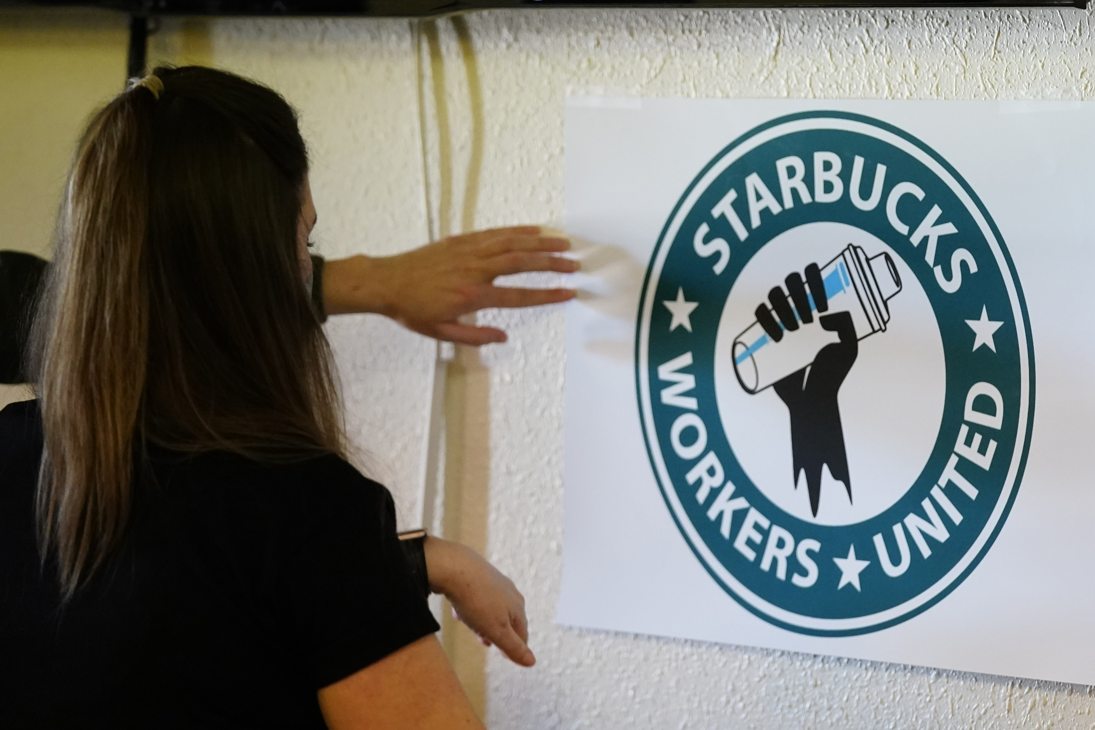 미국 메릴랜드 주에 위치한 ‘스타벅스’ 매장 직원이 노동조합 포스터를 붙이고 있다.