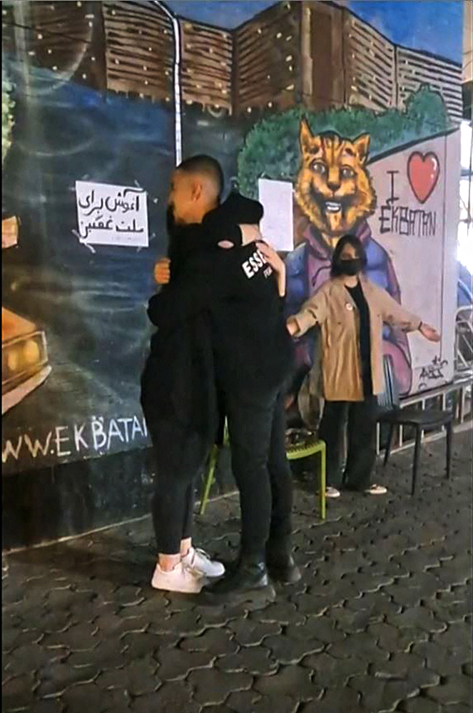 (테헤란 AFP=연합뉴스) 19일(현지시간) 이란 수도 테헤란에서 히잡을 쓰지 않은 두 여성이 지나가는 시민들을 포옹하며 격려하고 있다. 이들의 뒤에 있는 벽에는 ‘슬픈 이들에게 포옹을’이라는 내용의 페르시아어 문구가 적혀있다. 히잡을 제대로 착용하지 않았다는 이유로 풍속 경찰에 체포된 마흐사 아미니(22세)가 체포 사흘만인 지난달 16일 사망했다고 발표된 이후 이란에서는 줄곧 항의 시위가 이어지고 있다.