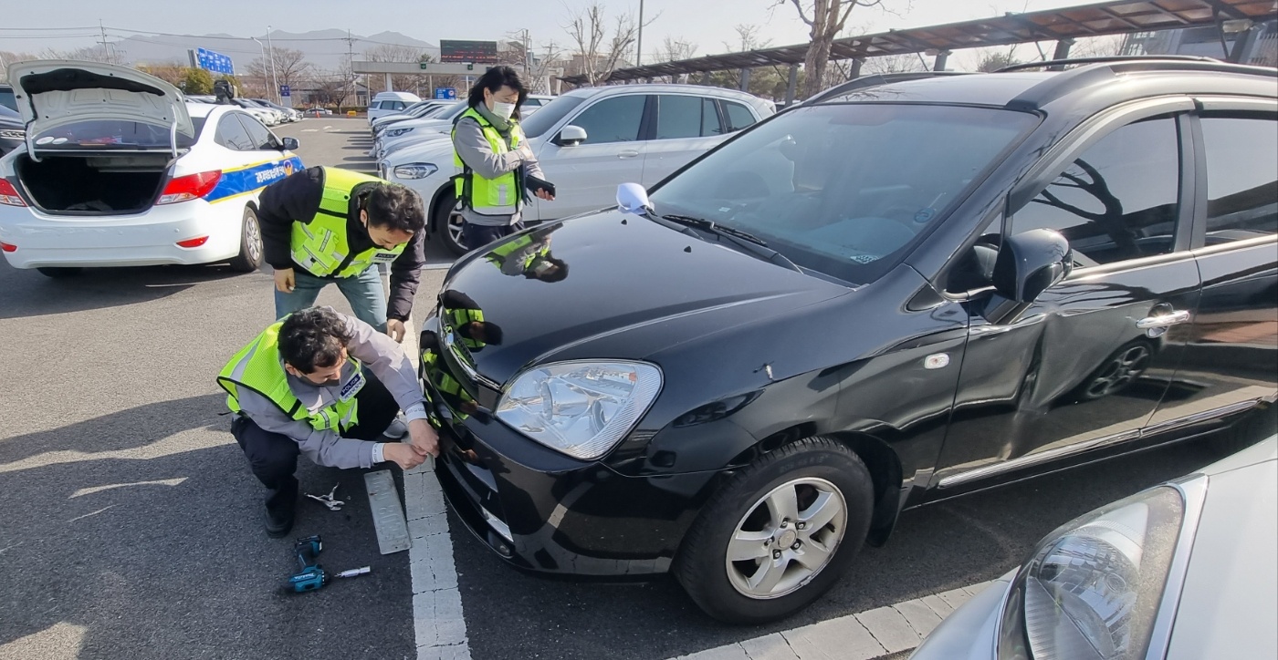 20일 오전 부산 김해국제공항 주차장에서 경찰관이 교통 과태료 체납 차량의 번호판을 떼어내고 있다.
