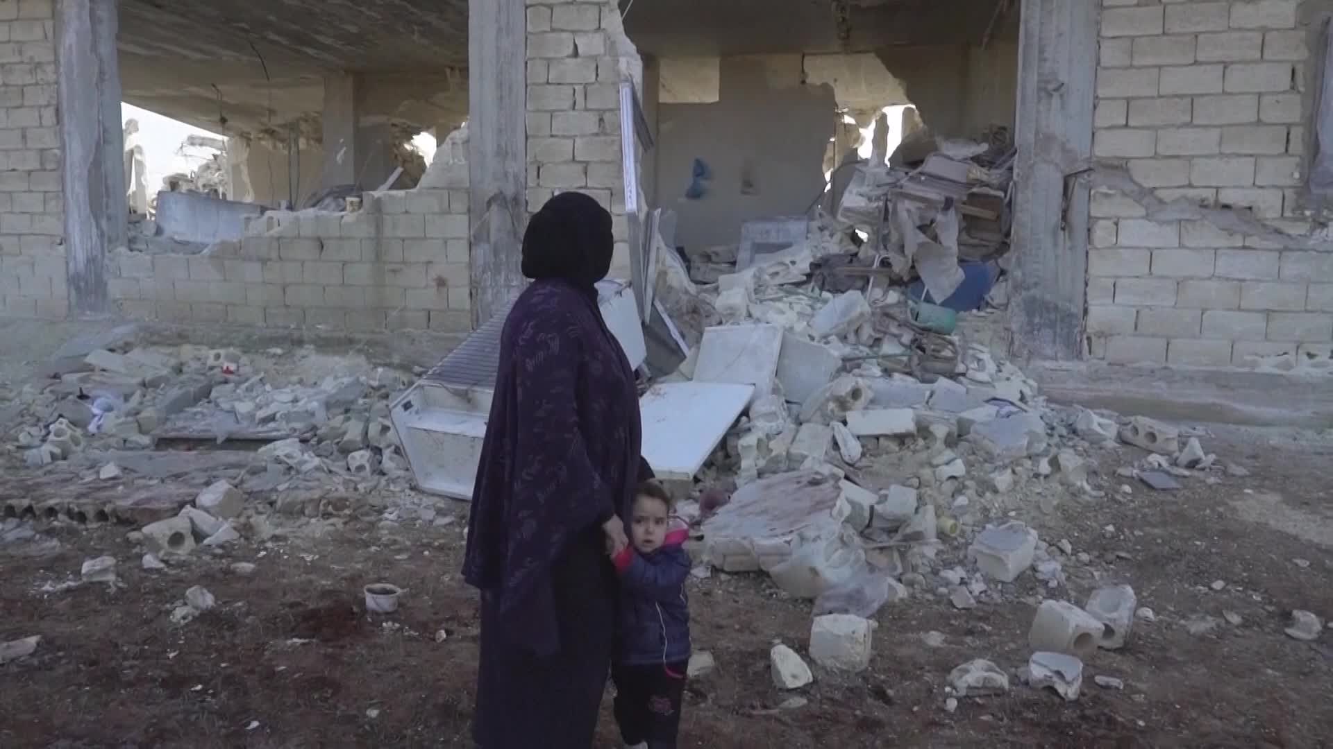 12일 시리아 알레포 주 아타립에서 아이샤가 손녀와 함께 무너진 집을 보는 모습.