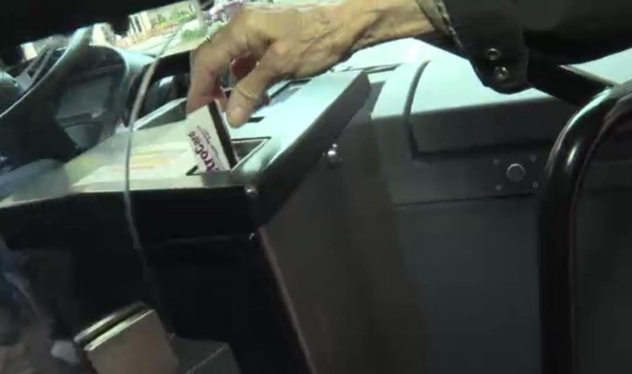 승객이 버스에 타면서 교통카드를 카드 인식기에 넣고 있다