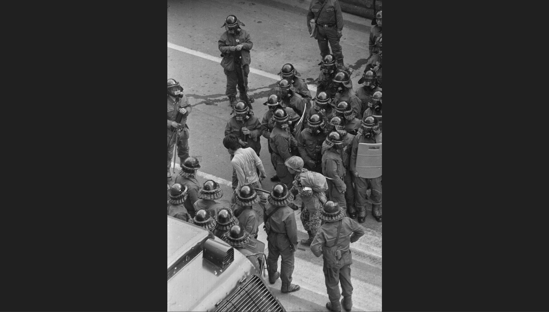 1980년 5월 19일, 광주 금남로에 서 있는 전경 부대 사이로 한 시민과 계엄군이 지나가고 있다. (사진 제공: 나경택)