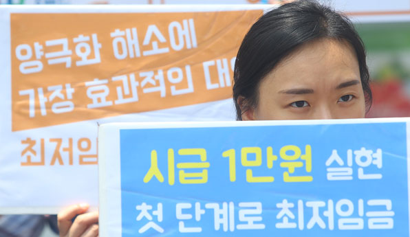 7월 12일 오후 서울 종로구 정부서울청사 앞에서 열린 최저임금 인상 촉구 경제정의실천시민연합 합동 기자회견에서 참가자가 구호가 적힌 피켓을 들고 있다. 