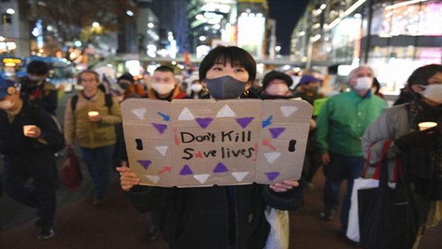 한 참가자가 12월 6일 여성 노숙인을 추모하기 위한 촛불집회에서 “생명을 죽이지 말고 살리라”는 내용을 손팻말을 들고 있다. 〈마이니치신문〉