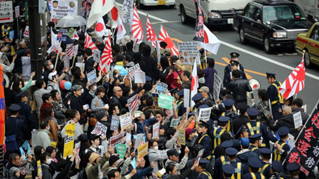 2016년 3월 일본 도쿄 도심에서 재일 조선학교 보조금 중단 등을 요구하는 시위대(오른쪽)가 행진하고 있고, 이에 반대하는 시민들(왼쪽)이 피켓을 들어 항의하고 있다. 〈연합뉴스〉