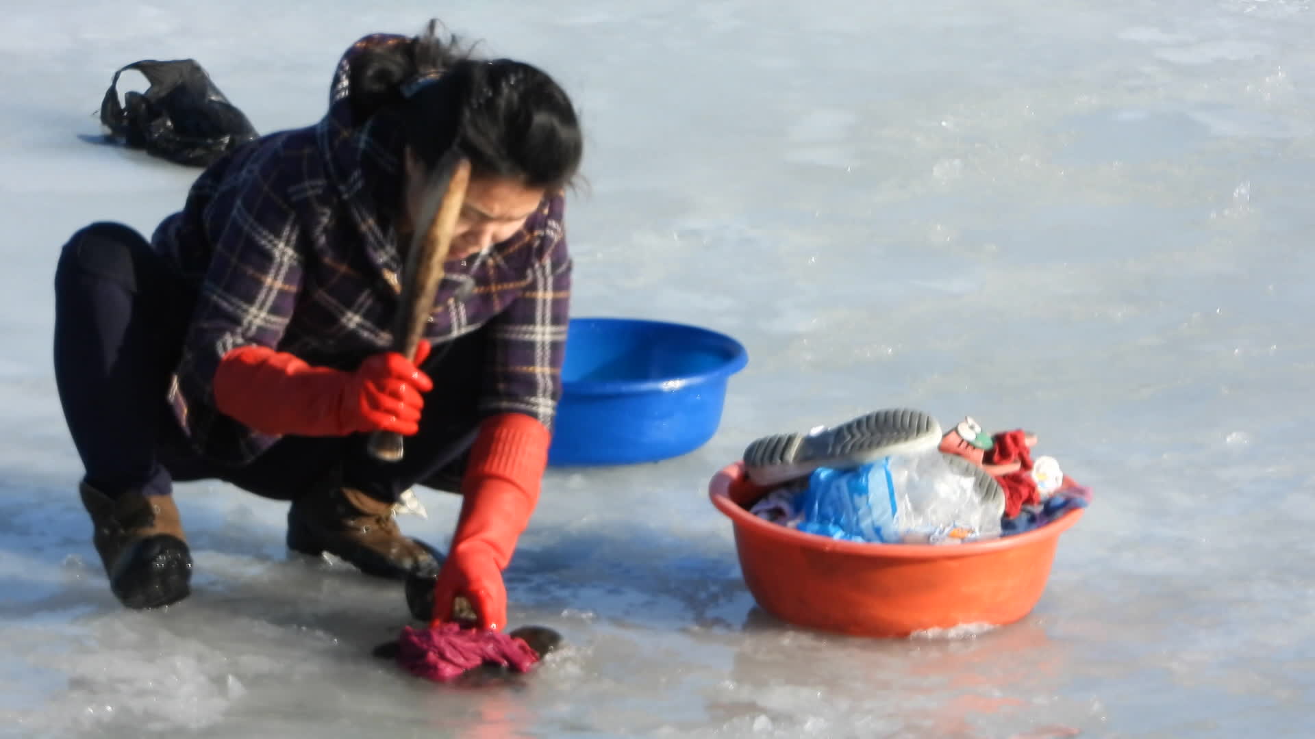북한 평안북도 중강진에서 한 주민이 강물 얼음을 깨고 빨래를 하고 있다.