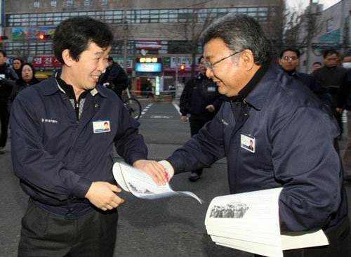 24일 오전 현대자동차 울산 4공장 정문에서 출근하던 한 근로자(왼쪽)가 노사협상 완전 타결 소식이 담긴 유인물을 나눠주던 이경훈 금속노조 현대차 지부장의 손을 잡고 수고했다는 인사를 하고 있다.