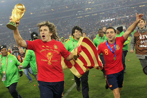 12일(한국시간) 남아프리카공화국(이하 남아공) 요하네스버그 사커시티에서 열린 2010 남아공월드컵 결승 스페인-네덜란드 경기에서 우승한 스페인의 카를레스 푸욜(왼쪽)과 사비 에르난데스가 월드컵 트로피와 국기를 들고 팬들에게 달려가고 있다.