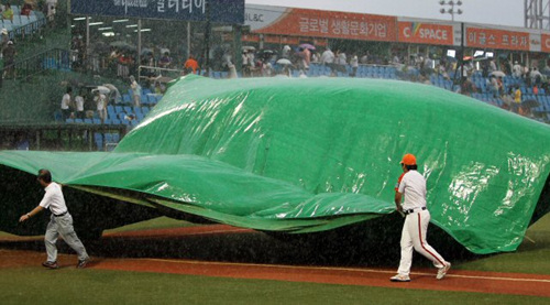 21일 대전 한밭야구장에서 열린 프로야구 한화와 롯데의 경기가 갑작스렇게 내린 비로 인해 중단돼 관계자들이 천막으로 투수 마운드를 덮고 있다.