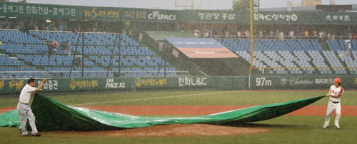 21일 대전 한밭야구장에서 열린 프로야구 한화와 롯데의 경기가 갑작스렇게 내린 비로 인해 중단돼 관계자들이 천막으로 투수 마운드를 덮고 있다.
