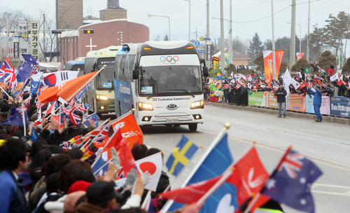 17일 강원 평창군 진부면 일대에서 주민들이 현지실사에 나선 IOC 조사평가위원을 태운 버스가 지나가자 깃발을 흔들며 환영하고 있다.