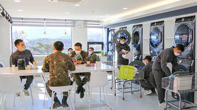 육군 51사단 장병들이 병영 빨래방에서 세탁기와 건조기를 이용하면서 책을 읽고 있다. [사진 제공 : 육군]