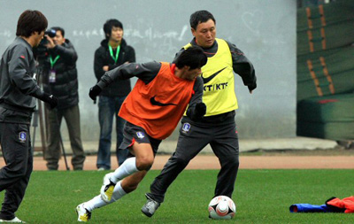 중국 충칭에서 열리는 동아시아 선수권 축구대회 대 중국전에서 승리를 거둔 국가대표팀 허정무 감독이 노란색 조끼를 입고 직접 게임을 하며 수비수를 따돌리고 있다. 