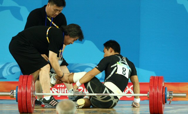12일 베이징 항공항천대에서 열린 베이징올림픽 남자 역도 69kg급에 출전한 이배영이 용상 1차시기에 도전하다 넘어진 뒤 코치진과 부상부위를 살펴보고 있다. 