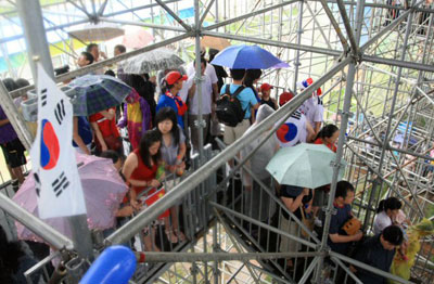 14일 베이징 우커송 야구장에서 열린 올림픽 야구 한국과 중국의 경기에서 폭우로 경기가 중단된 가운데 관중들이 계단에 몰려 비를 피하고 있다. 