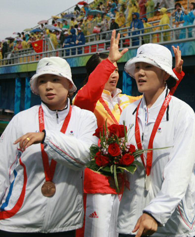 14일 베이징 올림픽 그린 양궁 경기장에서 열린 여자 개인전 결승에서 중국의 장 쥐안쥐안이 우승의 기쁨을 나누고 있는 동안 은메달에 그친 박성현과 동메달 윤옥희가 경기장을 나서고 있다. 