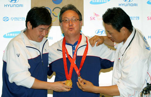 진갑용과 이승엽이 24일 오전 베이징 프라임호텔 '코리아하우스'에서 기자회견을 가진 뒤 김경문 감독에게 금메달을 걸어주고 있다. 
