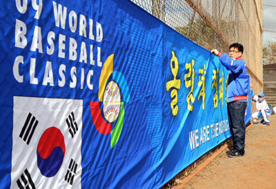   WBC 야구대표팀이 하와이 호놀룰루 센트럴 오아후 리저널파크에서 전지훈련을 시작한 17일 오전(한국시간) KBO 직원들이 '올림픽 챔피언 우리가 간다'라고 적힌 현수막을 훈련장에 설치하고 있다. 