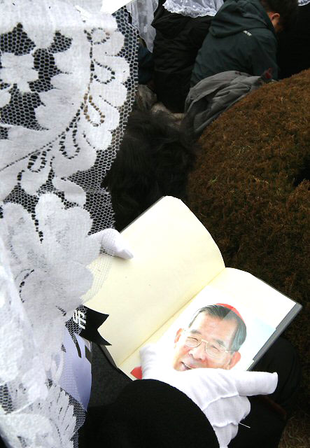  22일 오후 경기도 용인 천주교 성직자 묘역에서 열린 故 김수환 추기경 추모 미사에 참여한 한 신자가 김 추기경의 환한 웃음을 담은 사진을 들고 기도하고 있다. 