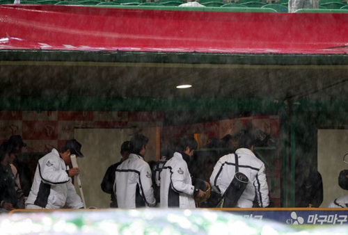 13일 인천 문학구장에서 열린 프로야구 플레이오프 5차전 SK와이번스-두산베어스 2회초에 폭우로 경기가 중단되자 두산 선수들이 더그아웃에서 짐을 꾸리고 있다. 